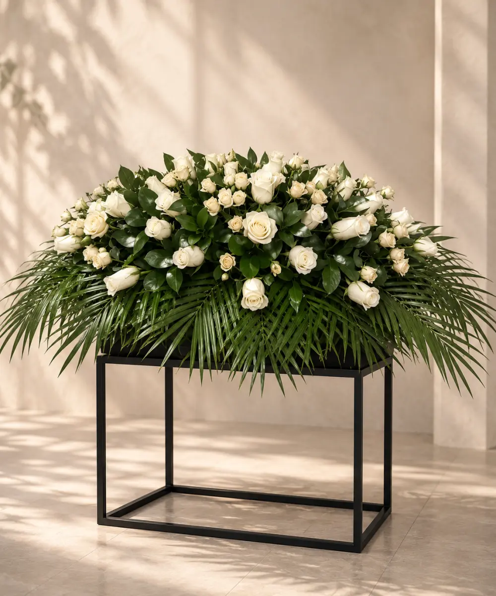 Casket spray of cream roses with palm leaves